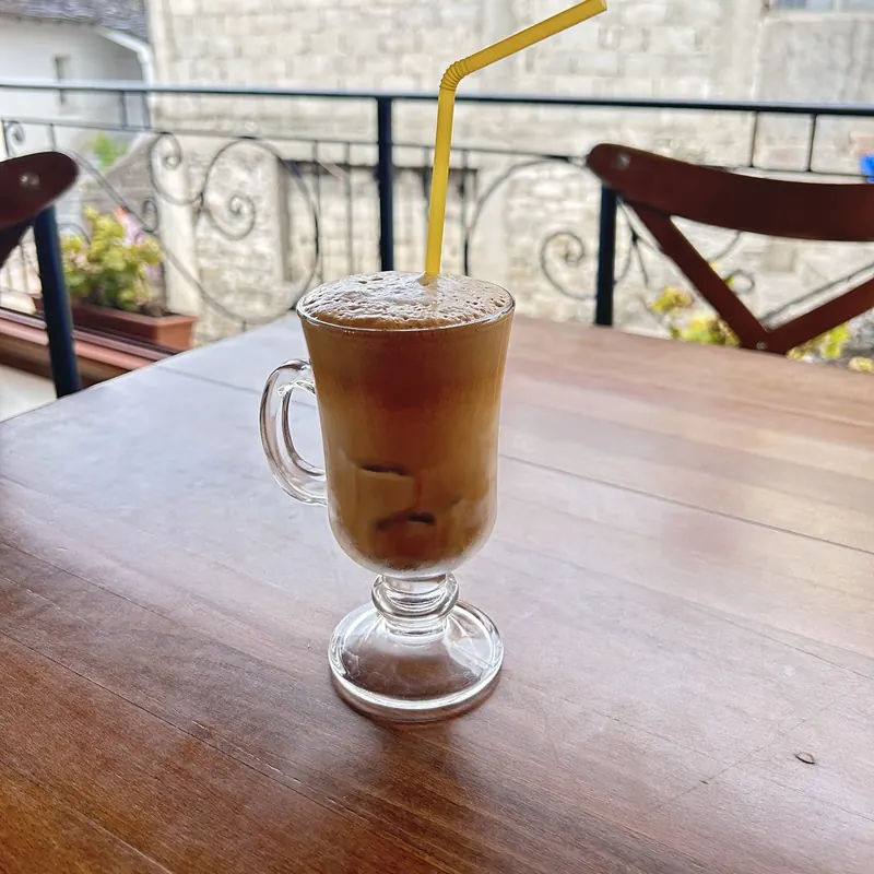 An iced frappe on a wooden table on the balcony