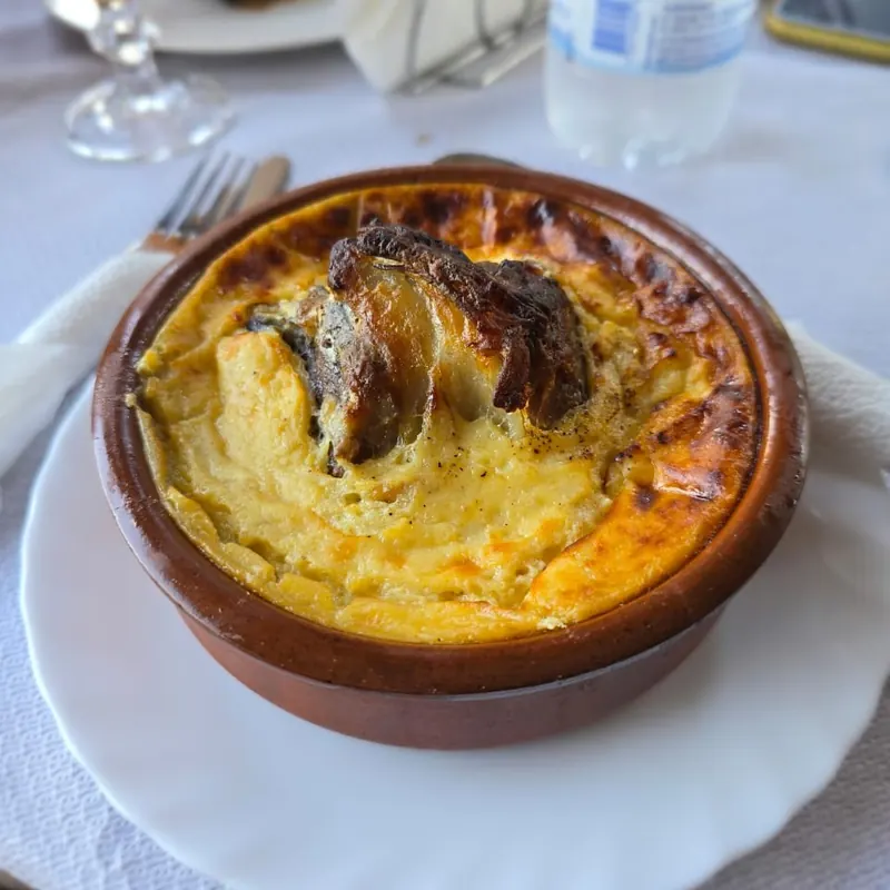 A baked dish with eggplant, golden on top, in a clay pot