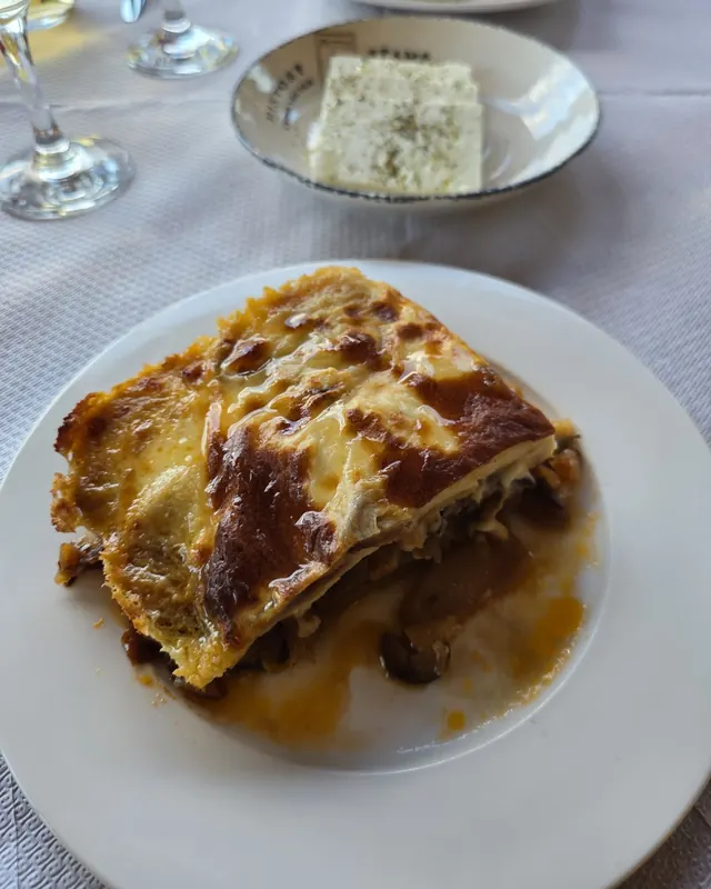 A golden, layered slice of moussaka on a white plate
