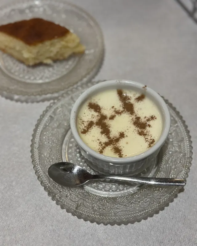 A bowl of oshaf, a creamy sheep's milk and fig pudding dusted with cinnamon, next to a slice of cake