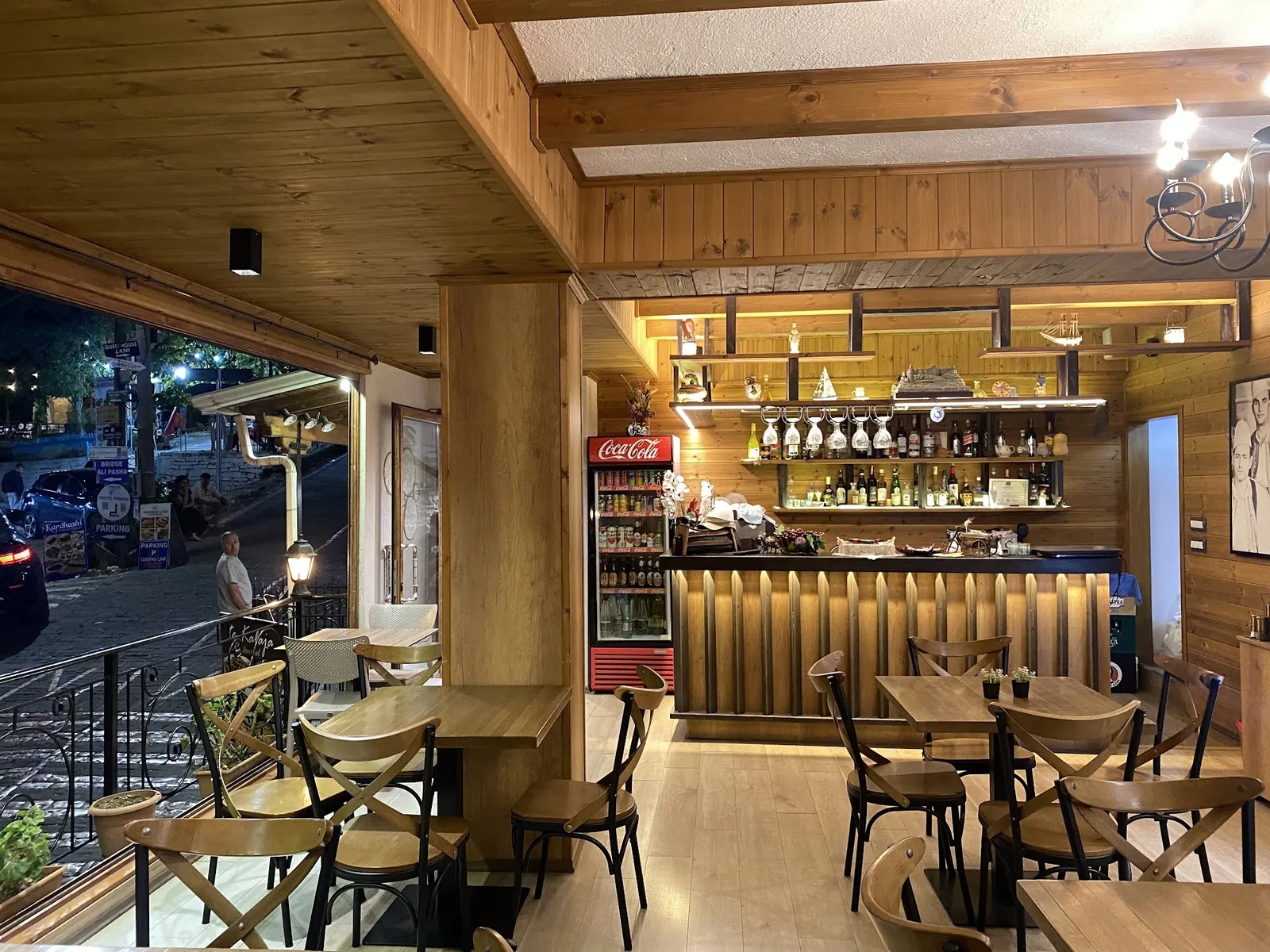 The wooden dining room and bar in the evening, with the open window onto the street
