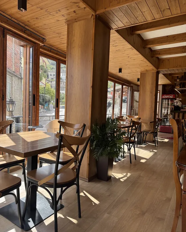 The dining room in daylight: wooden ceiling, tall windows and sunlight on the floor